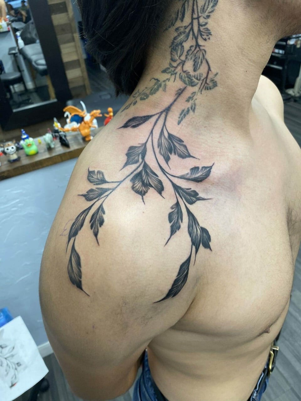 Black botanical branches spread from the side of the neck across a shoulder.