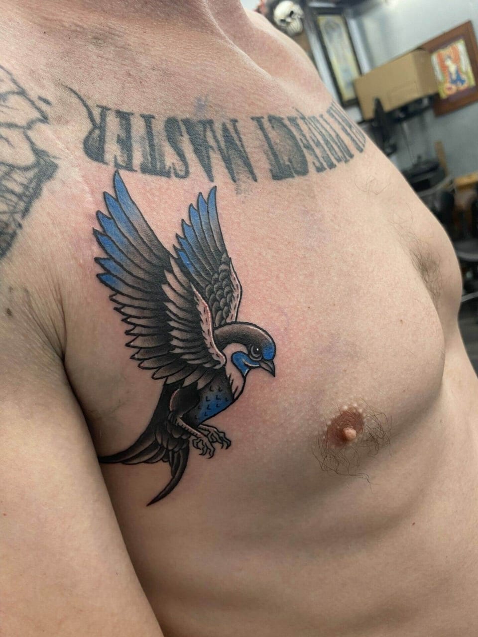A traditional blue swallow spreads its wings on the chest below lettering.