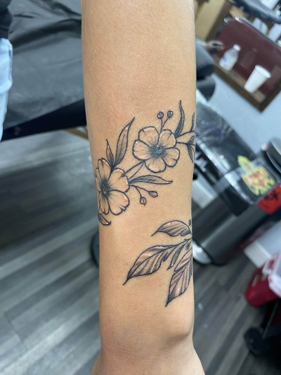 Black illustrative flowers and leaves wrap around a wrist.