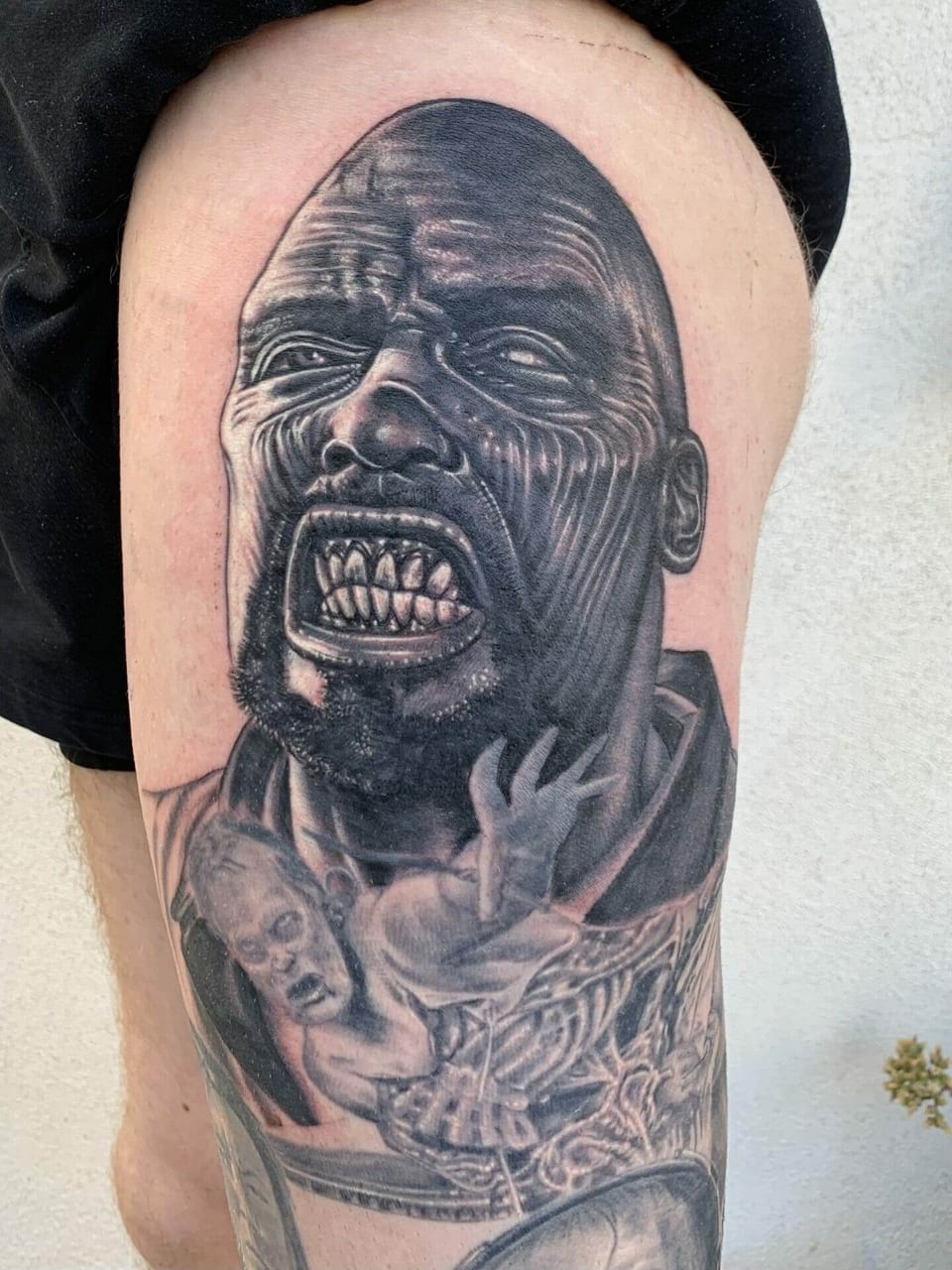 A black and grey zombie portrait with bared teeth covers the thigh.