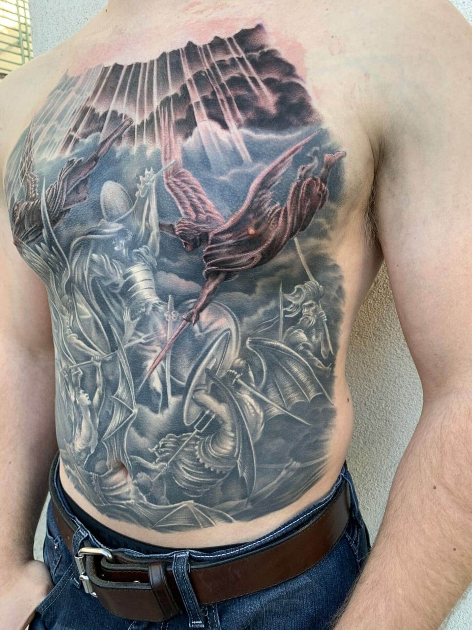 Black and grey armored knights, a winged angel and a dragon battle across the chest and abdomen.