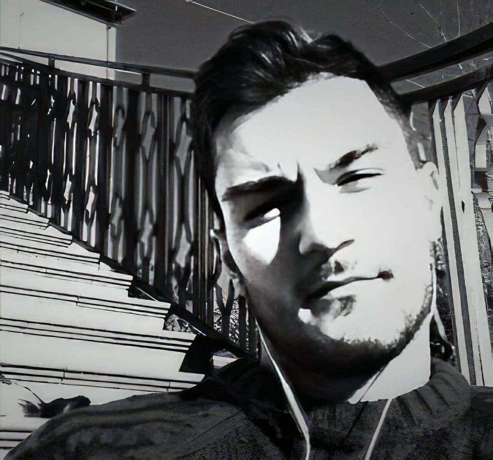 Diego Perugini looks toward the camera beside an outdoor staircase in black and white.