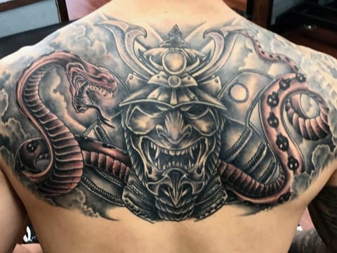 A black and grey samurai mask and helmet with red-accented snakes cover the upper back.