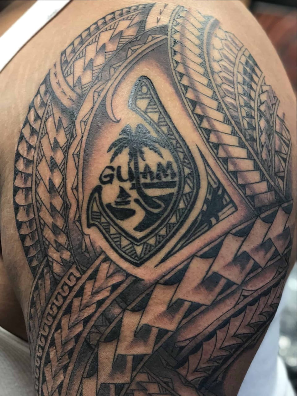 Polynesian shoulder piece with the Guam seal at its center, tattooed by Seth Reynolds