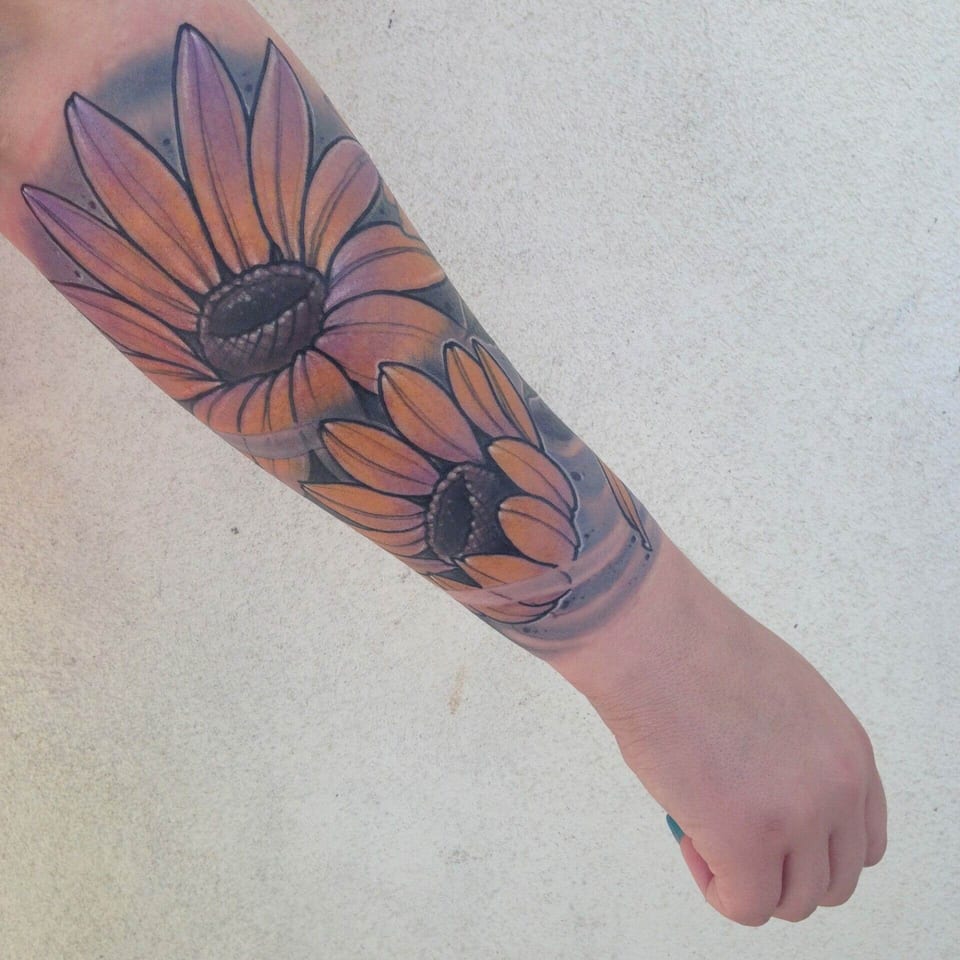 Orange neo-traditional sunflowers with dark centers and grey flowing bands cover the forearm.