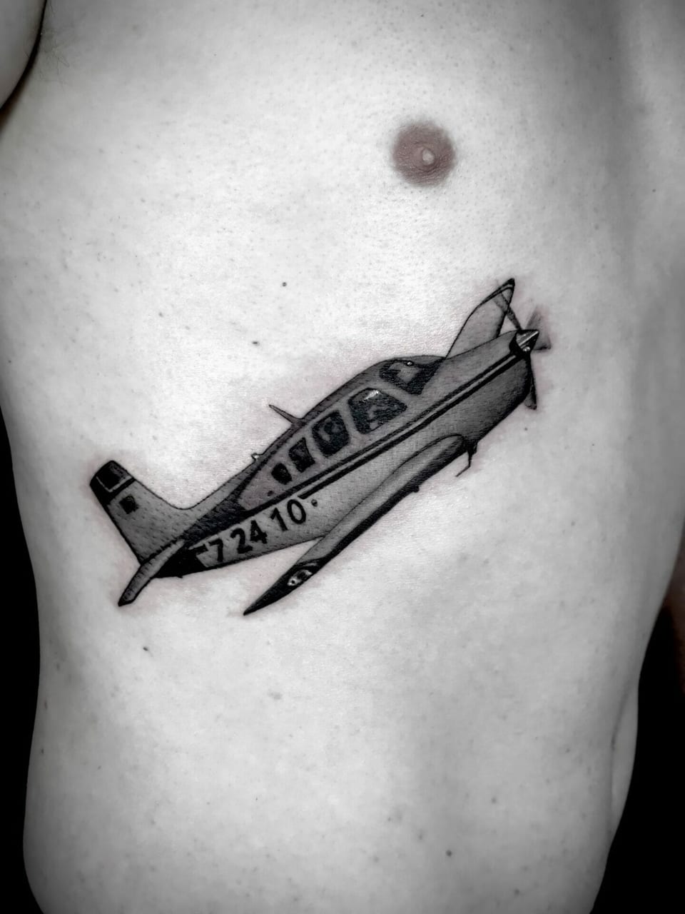 A black and grey propeller plane angles upward across the ribs.