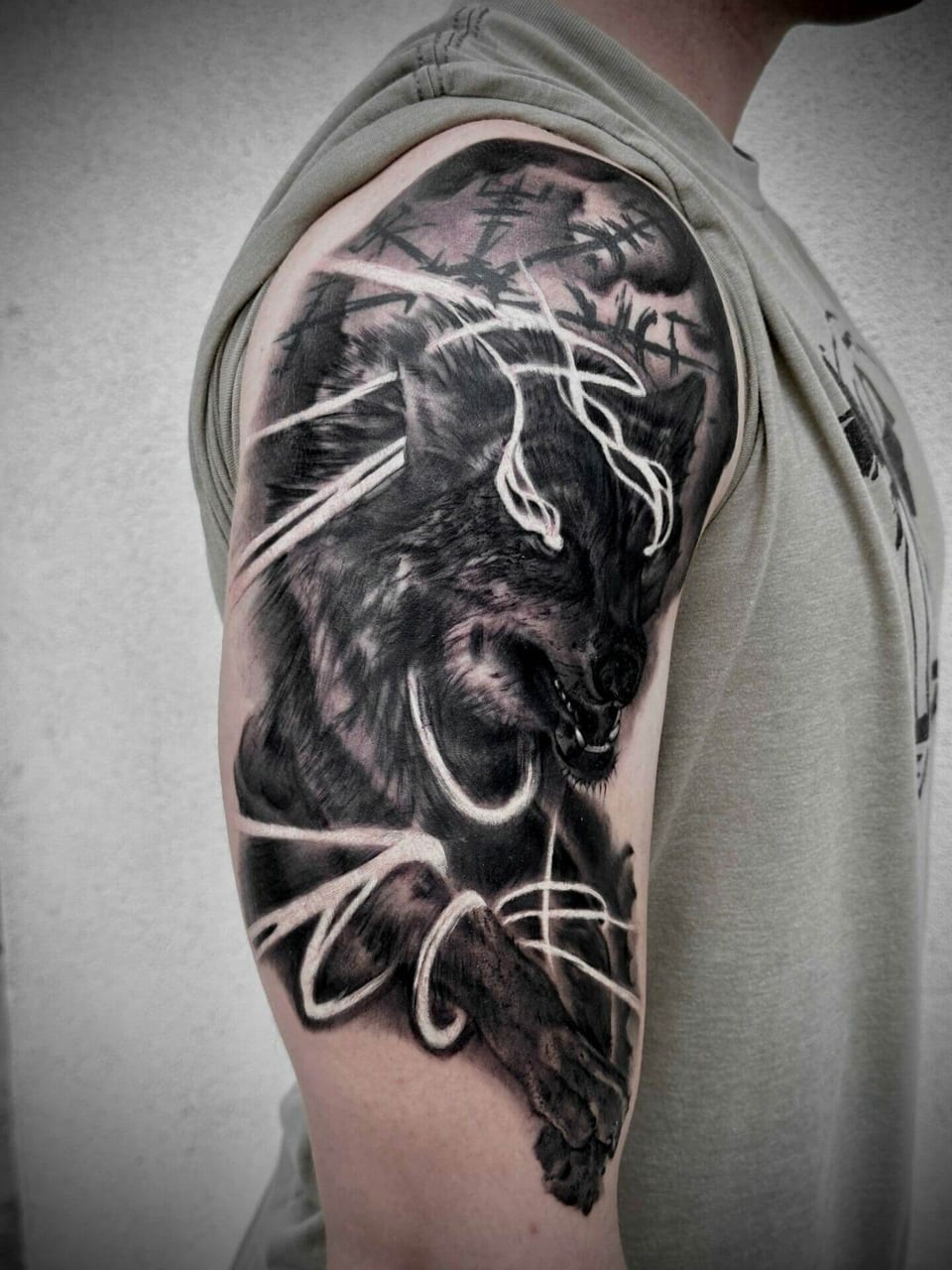 A black and grey snarling wolf and lightning-like white lines fill an upper arm.
