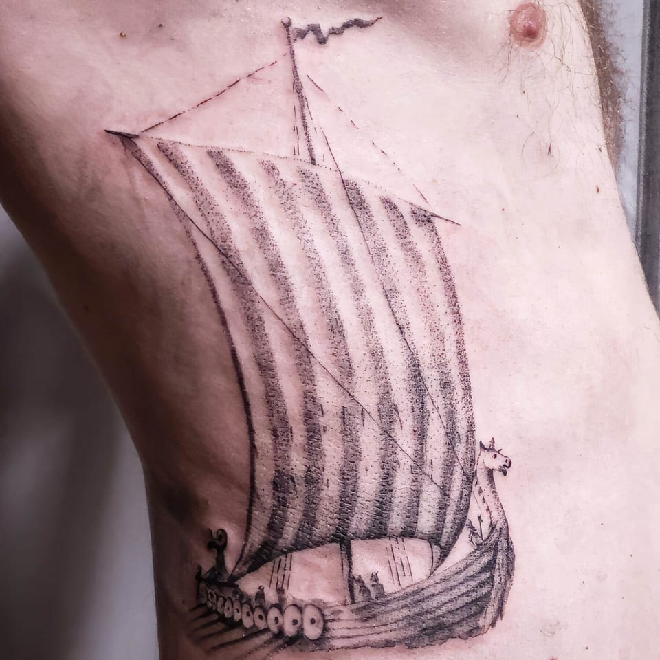 A dotwork Viking longship with a striped sail and rows of shields covers the ribs.