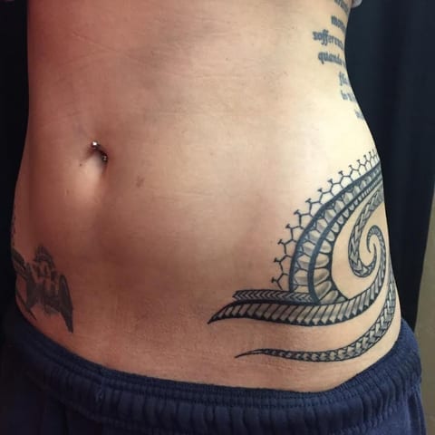 Polynesian curls across a woman's hip and belly, tattooed by Seth Reynolds