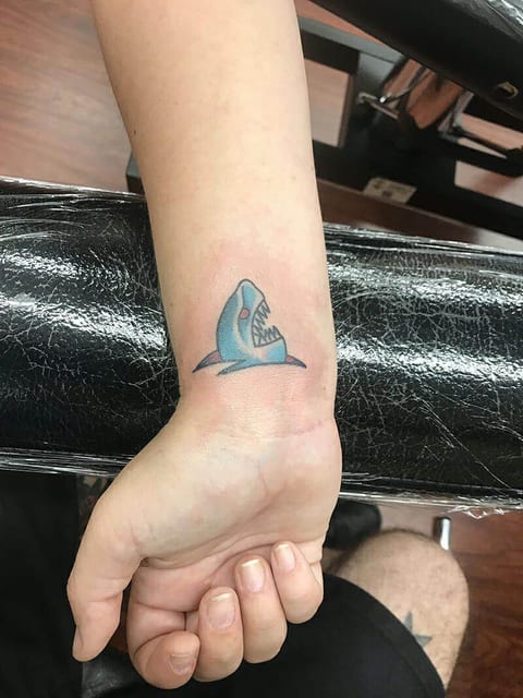 A traditional blue shark with red eyes and an open mouth appears near the wrist.