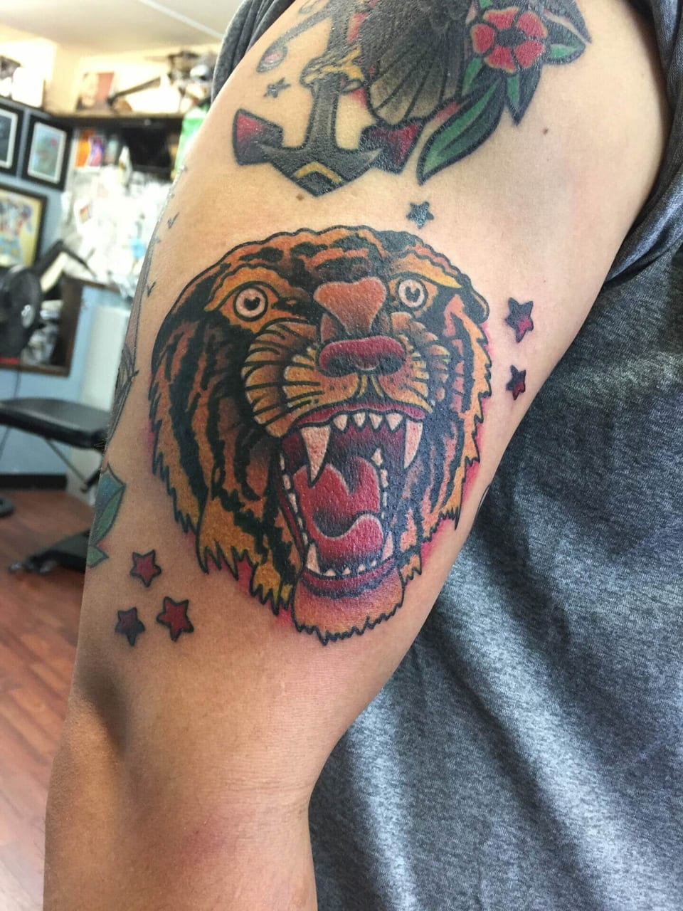 A traditional orange tiger head bares its fangs among small stars on the upper arm.