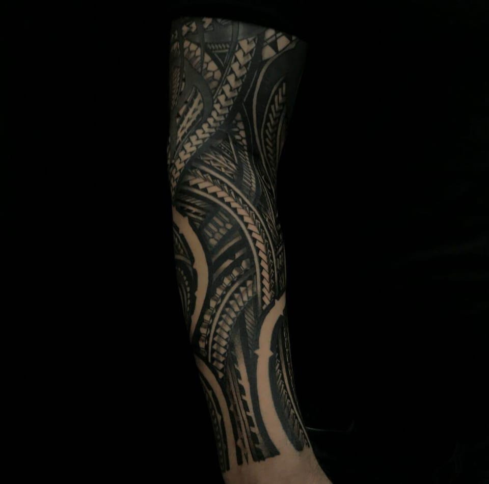 Polynesian band pattern on a limb against a black background, tattooed by Seth Reynolds