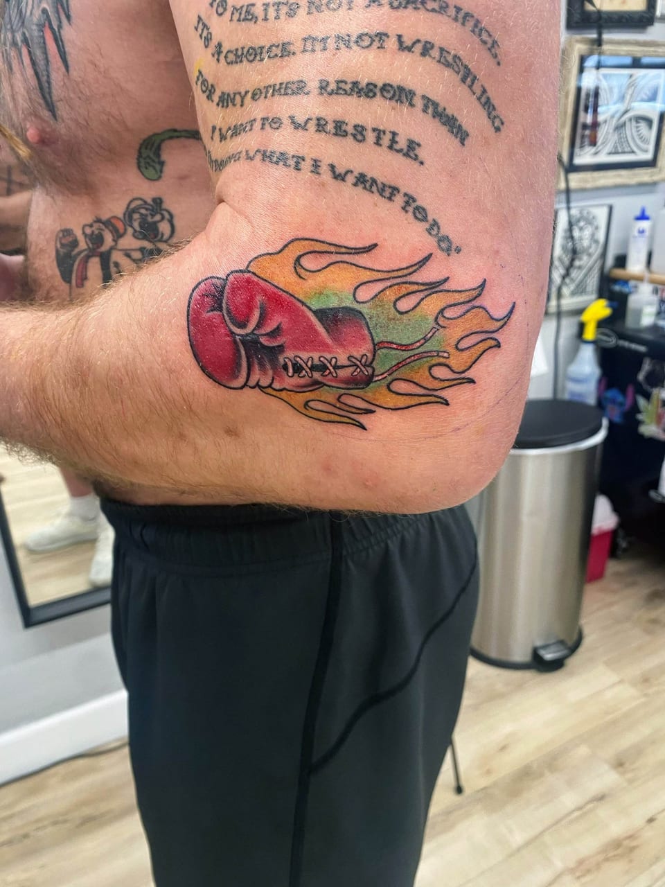 A traditional red boxing glove trails yellow and green flames on the elbow.