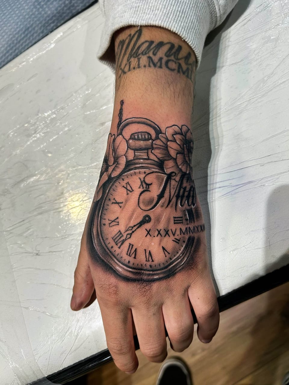 A black and grey realism pocket watch with flowers and script covers the hand.