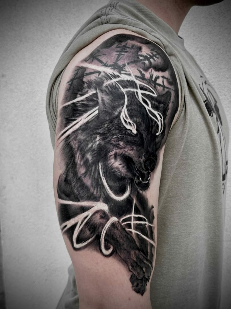 A black and grey illustrative snarling wolf framed by flowing lines covers an upper arm.