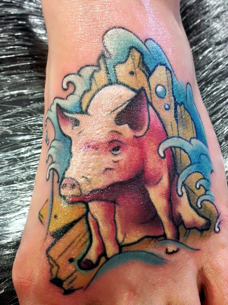 A color illustrative pig among blue waves and broken wooden planks covers the top of a foot.