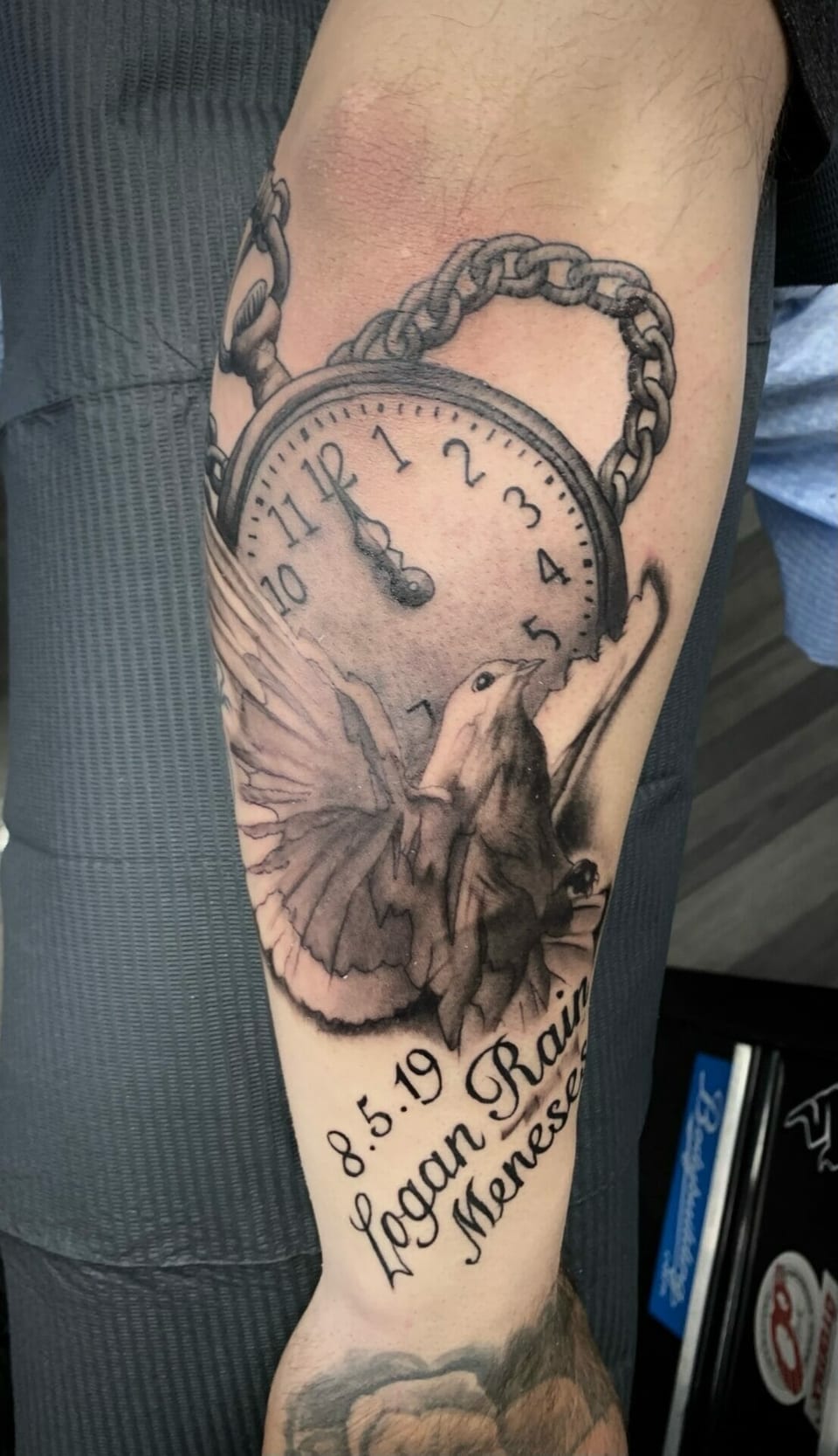 A black and grey realism pocket watch and flying dove cover a forearm.