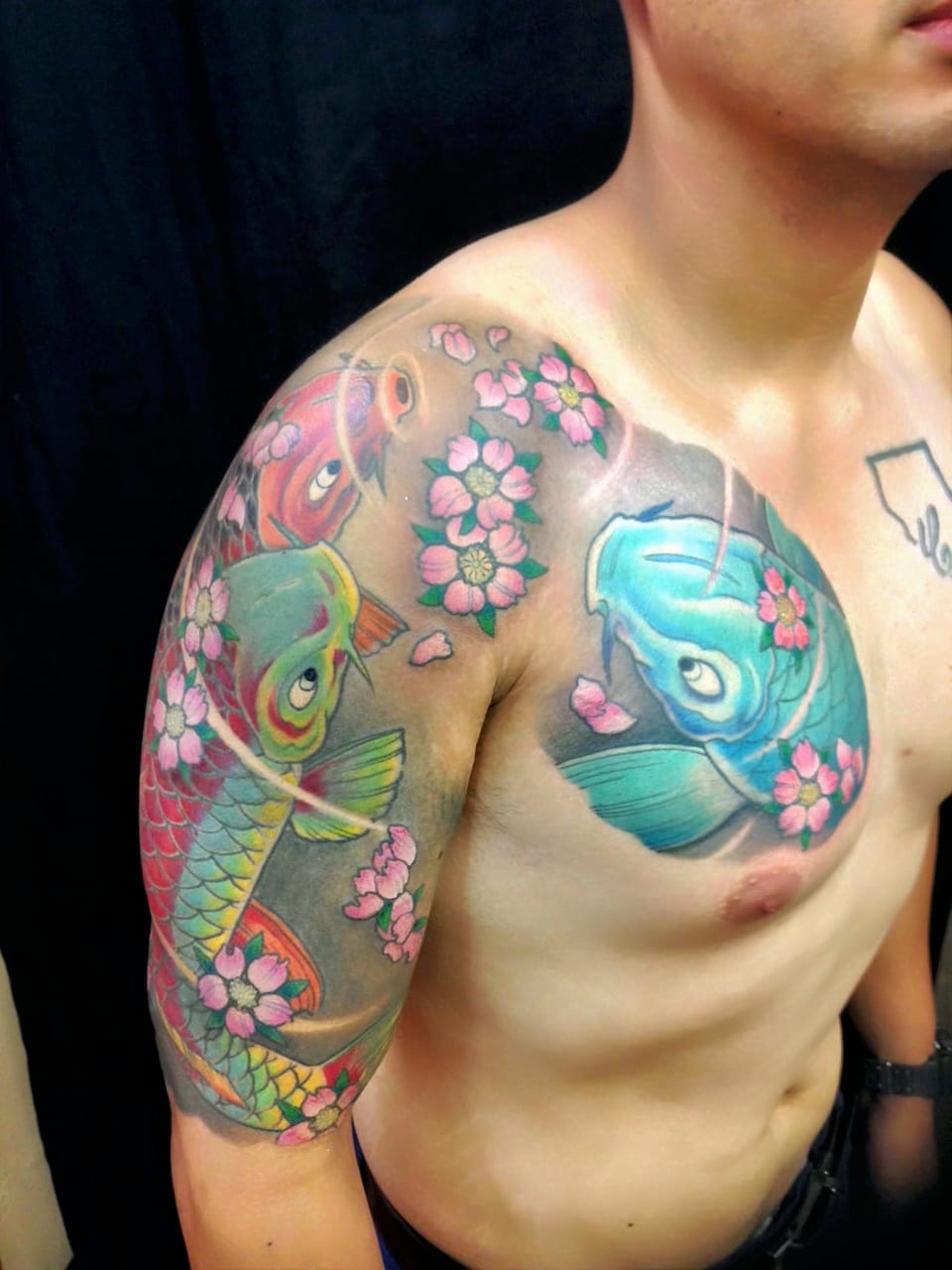 Color Japanese koi and pink blossoms span an upper arm, shoulder and chest.