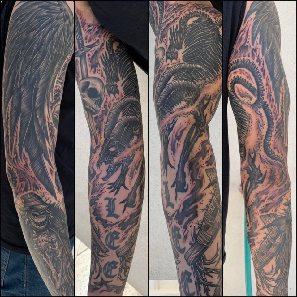 Black and grey horror sleeve with wings, skulls and gothic lettering covers the arm in several views.