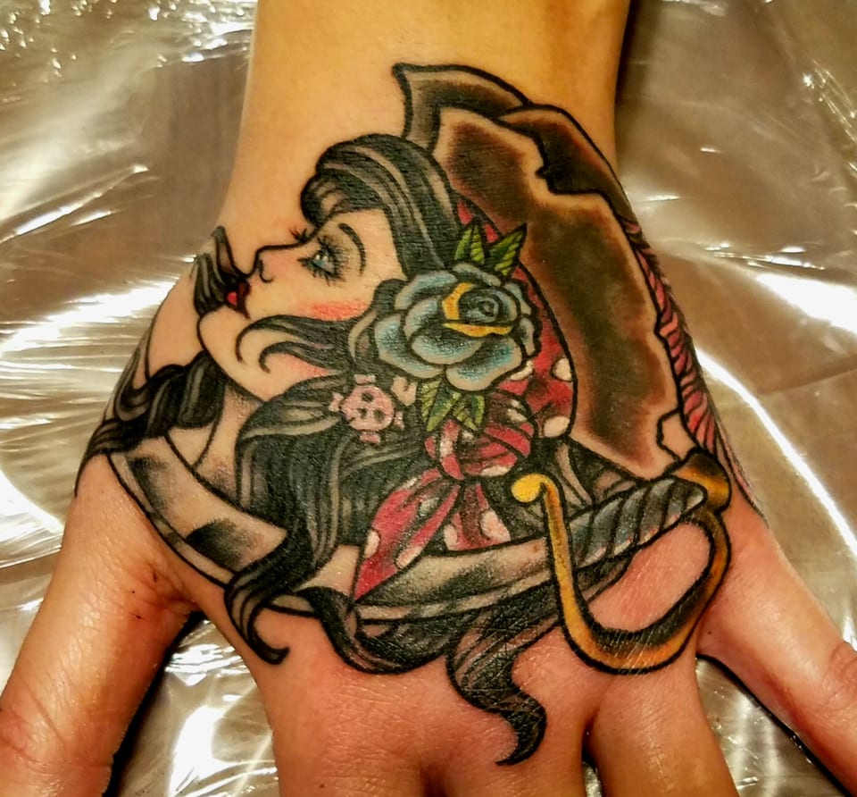 A traditional pirate woman with roses and a sword tattooed on a hand.