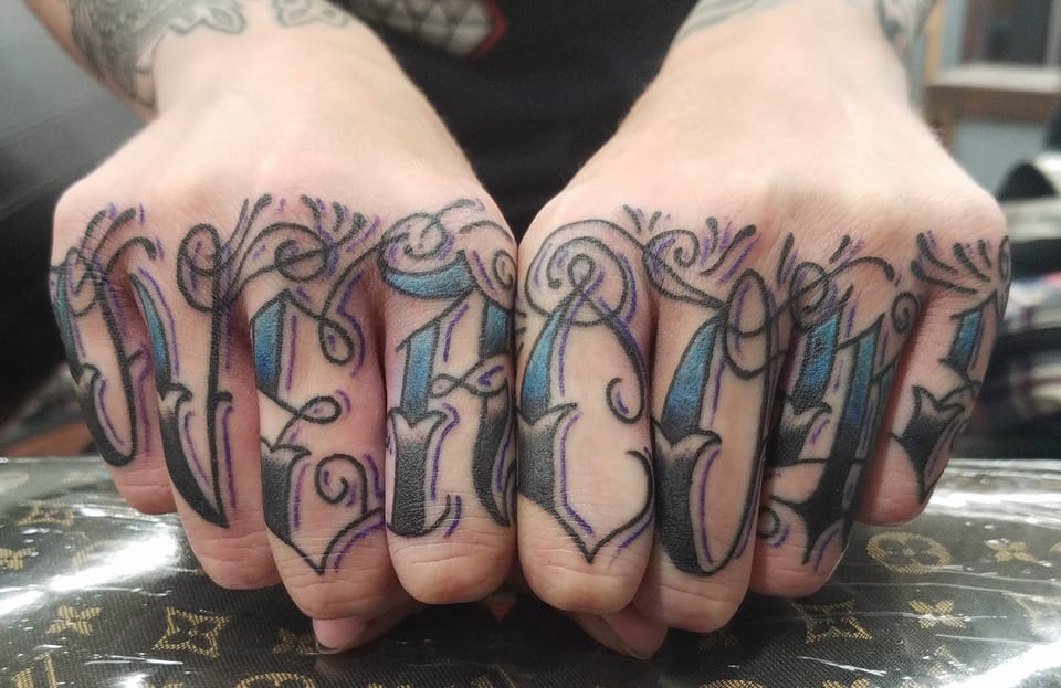 Ornate outlined lettering stretches across both sets of knuckles.