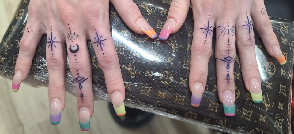 Fine black symbols and ornamental lines decorate both hands and fingers.