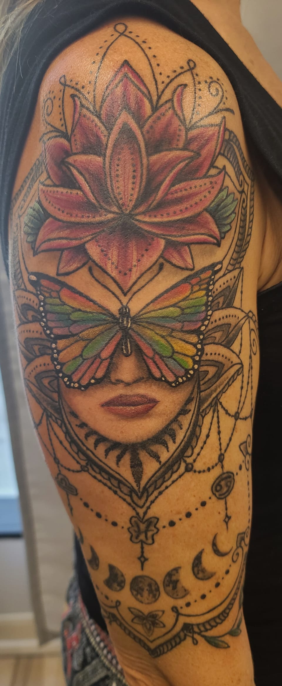 A woman with a lotus crown and geometric ornaments fills a tattoo.