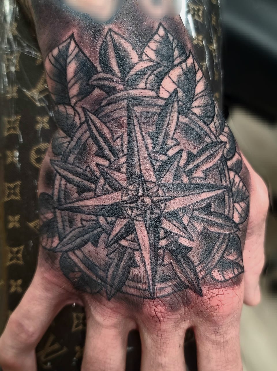 A geometric compass tattoo covers the back of a hand.