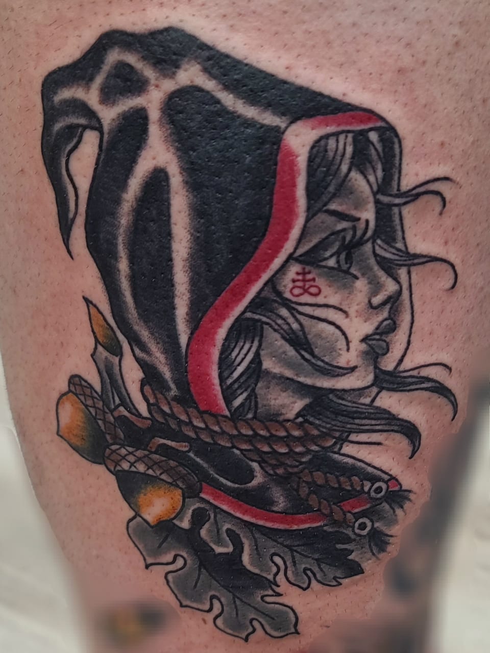 A black-hooded cat tattoo includes a red border and small ornaments.