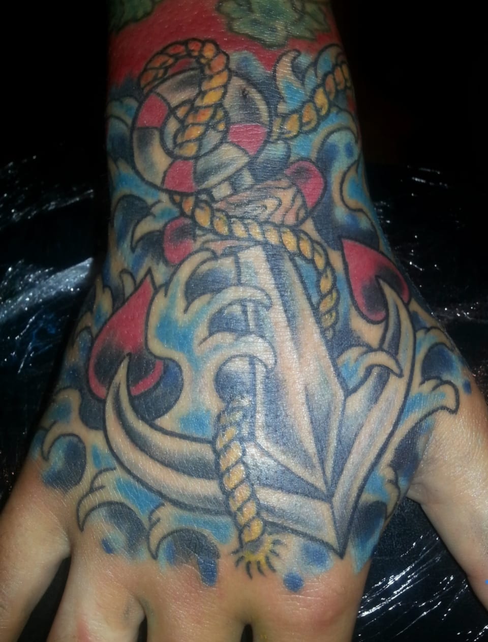 A colorful dagger and coiled snake cover the back of a hand.