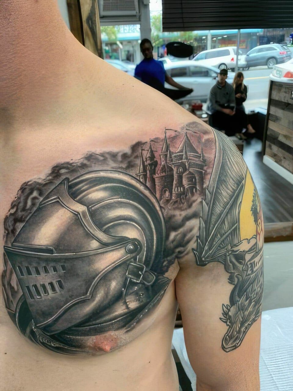 A black-and-grey realistic knight's helmet and castle span the chest and shoulder.