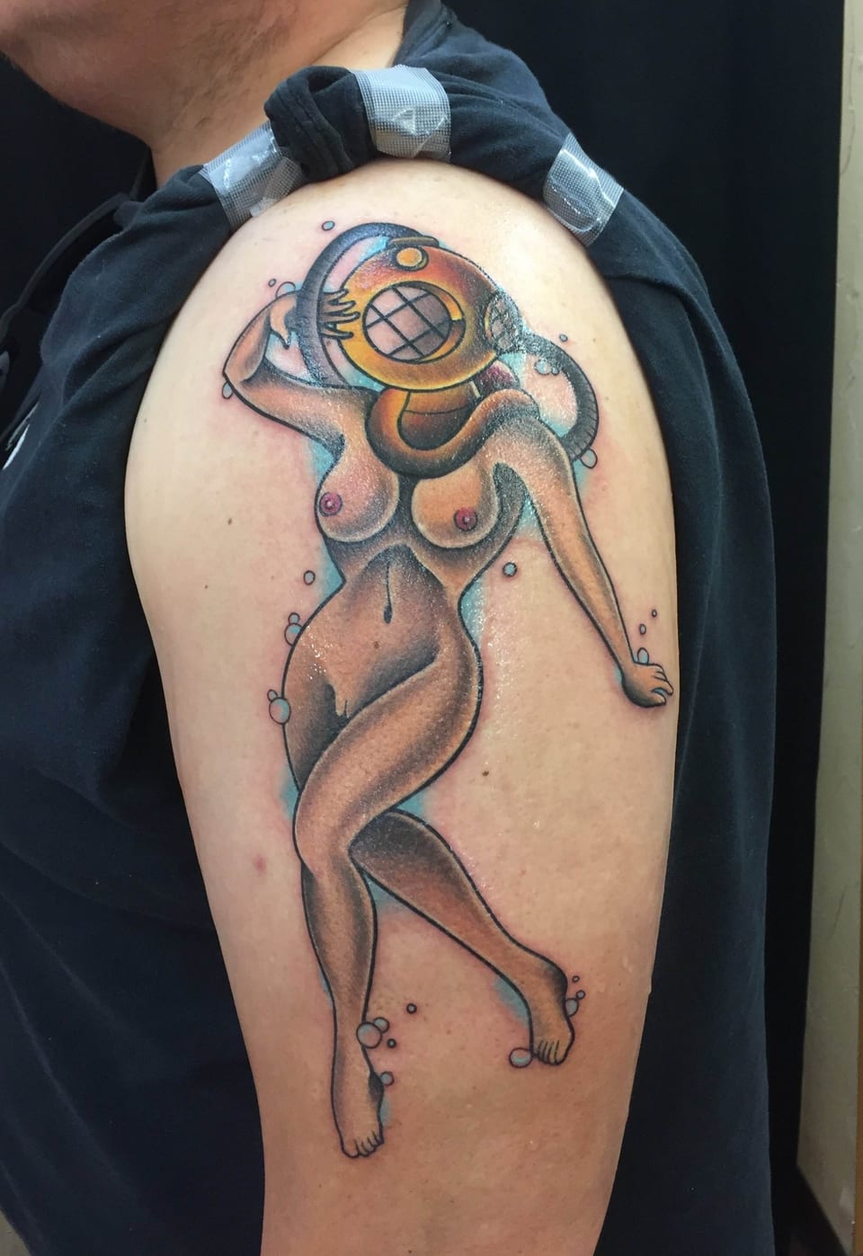 A colorful traditional pin-up diver wearing a helmet covers an upper arm.