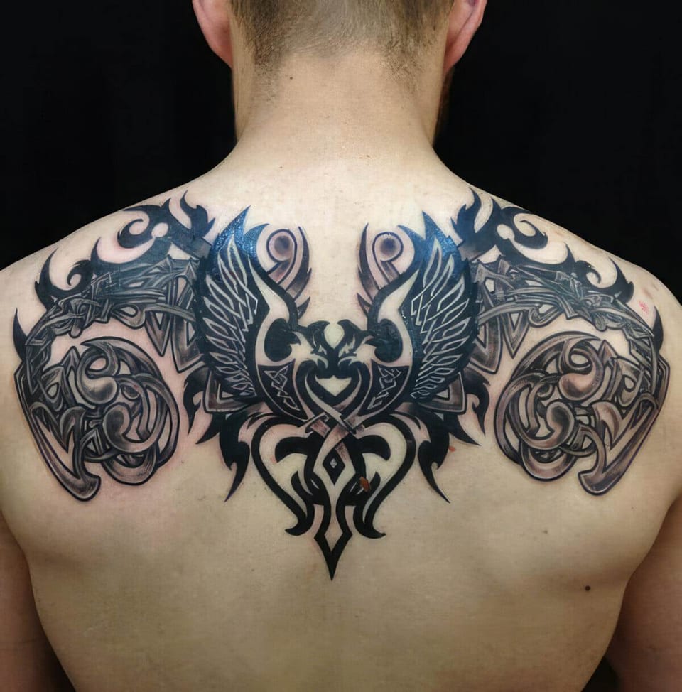 Black and blue tribal wings and swirls tattooed across an upper back, tattooed by Seth Reynolds