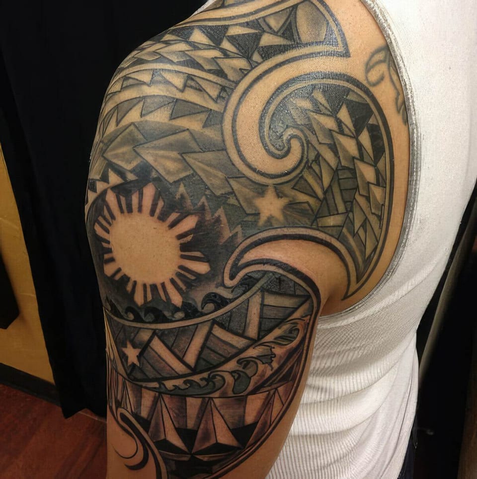 Black Polynesian-style sun pattern tattooed on a shoulder and upper arm, tattooed by Seth Reynolds