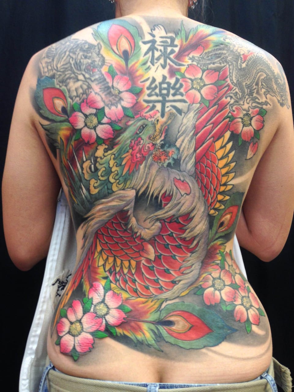 A colorful Japanese phoenix, blossoms, tiger, dragon and vertical characters span the back.
