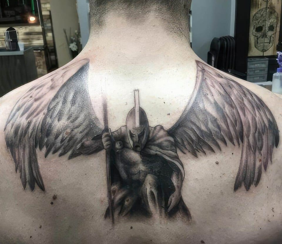 A black-and-grey realistic armored warrior with spread wings covers an upper back.