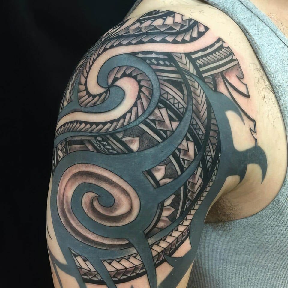 Black Polynesian-style shoulder piece with a large spiral and bold bands, tattooed by Seth Reynolds