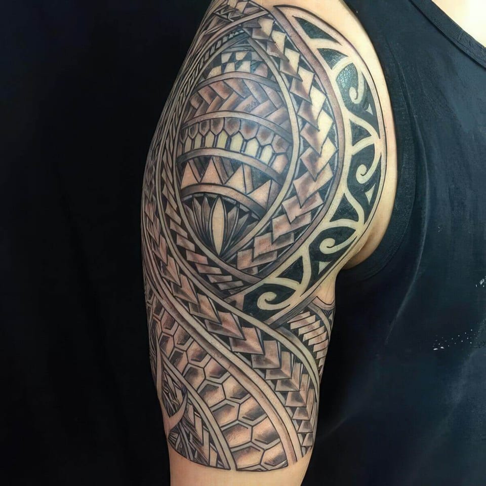 Black Polynesian-style shoulder and upper arm piece with triangles and hexagon patterns, tattooed by Seth Reynolds