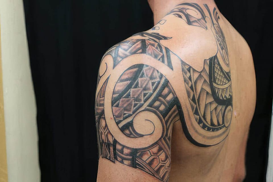 Black Polynesian-style spiral and wave pattern tattooed on a shoulder and upper arm, tattooed by Seth Reynolds