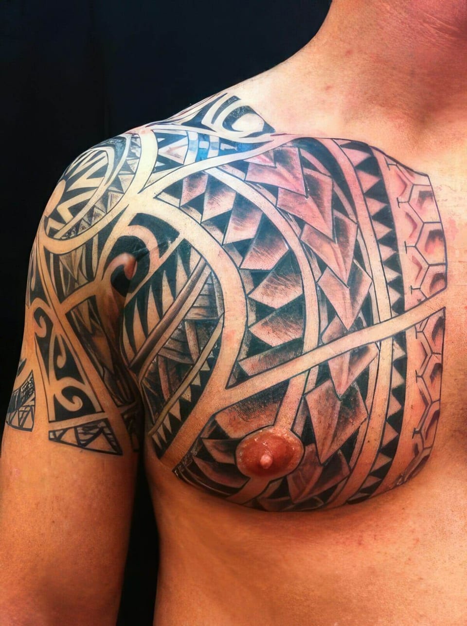 Black Polynesian-style tribal pattern covering a chest and shoulder, tattooed by Seth Reynolds