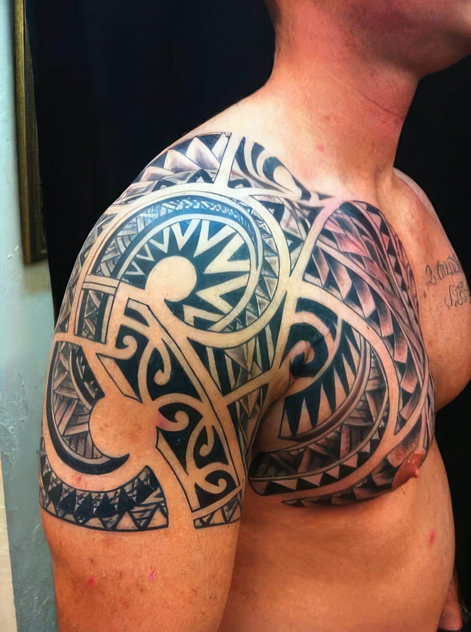 Black Polynesian-style spiral and wave pattern covering a chest and shoulder, tattooed by Seth Reynolds