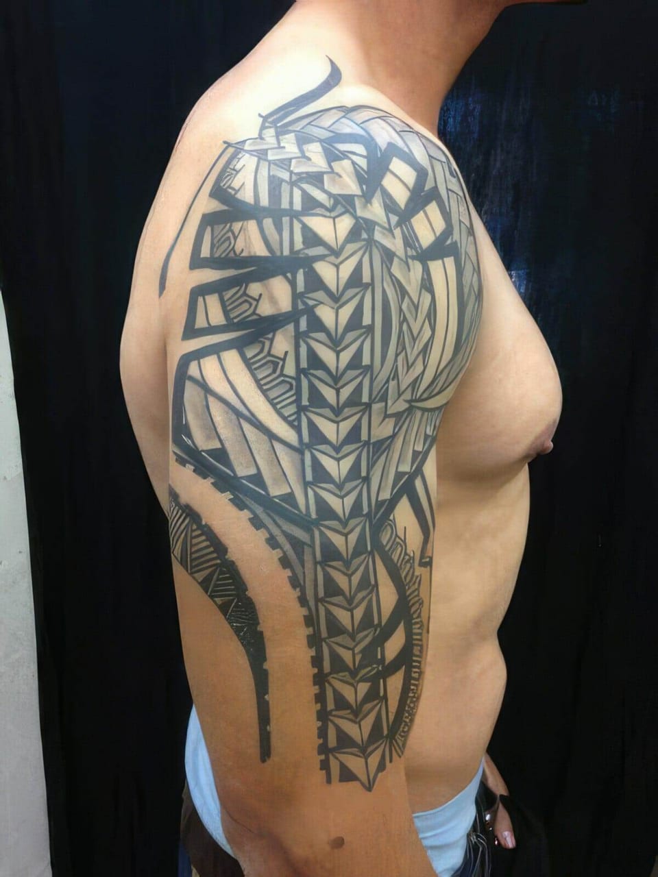 Black Polynesian-style tribal tattoo covering a shoulder, upper arm and side, tattooed by Seth Reynolds