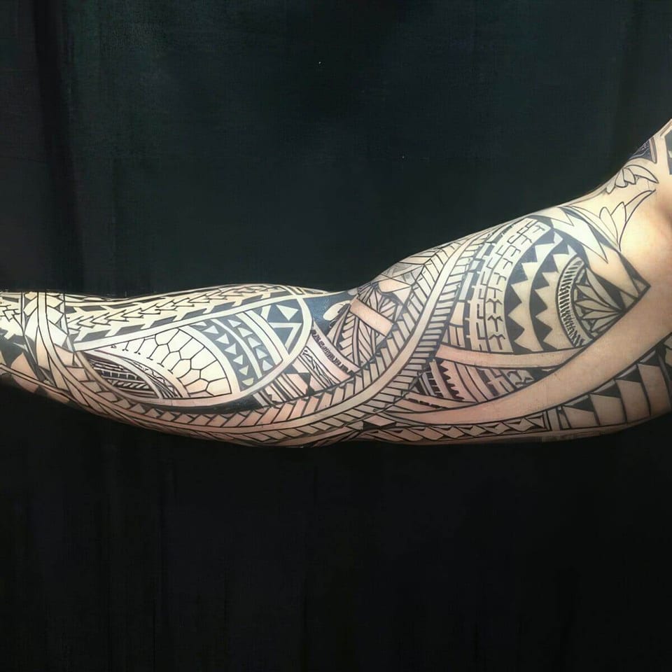 Black Polynesian-style full sleeve with woven bands tattooed along an arm, tattooed by Seth Reynolds