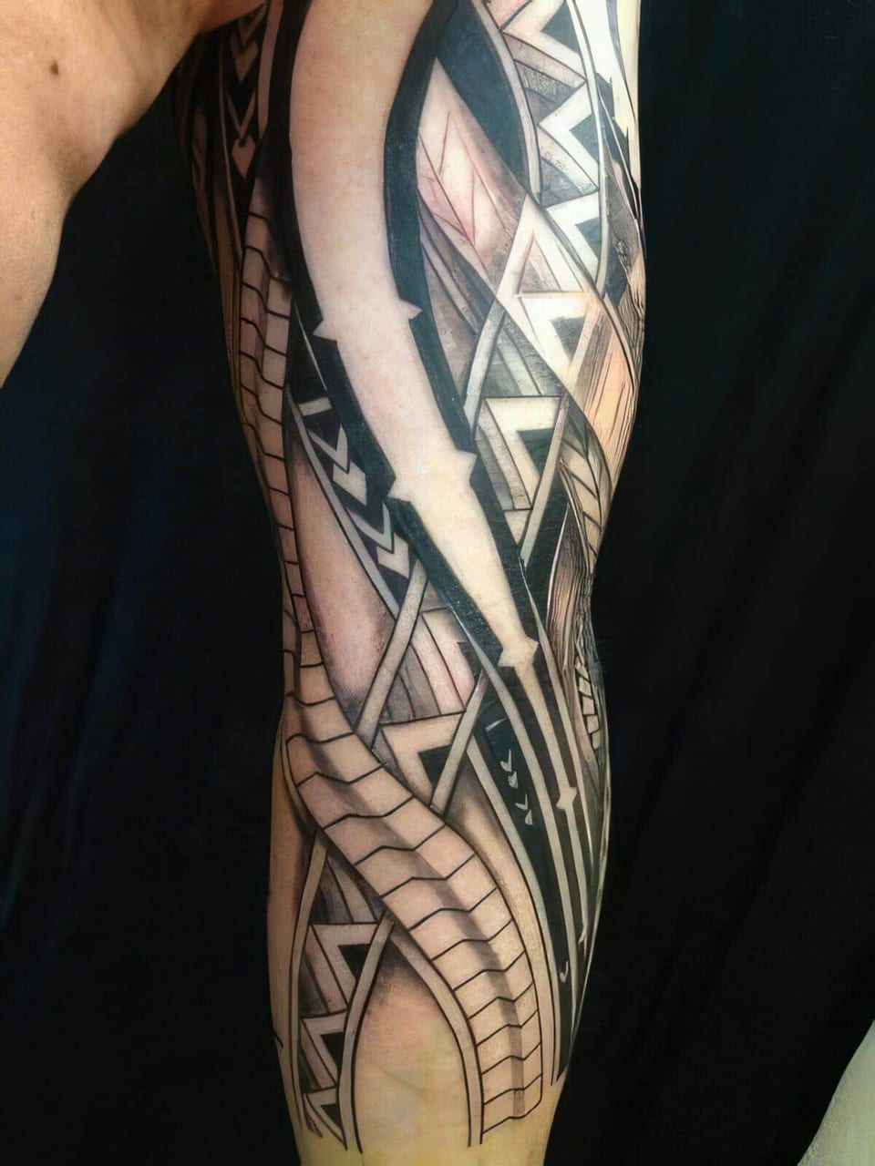 Black and grey Polynesian-style sleeve with geometric and woven patterns tattooed down an arm, tattooed by Seth Reynolds