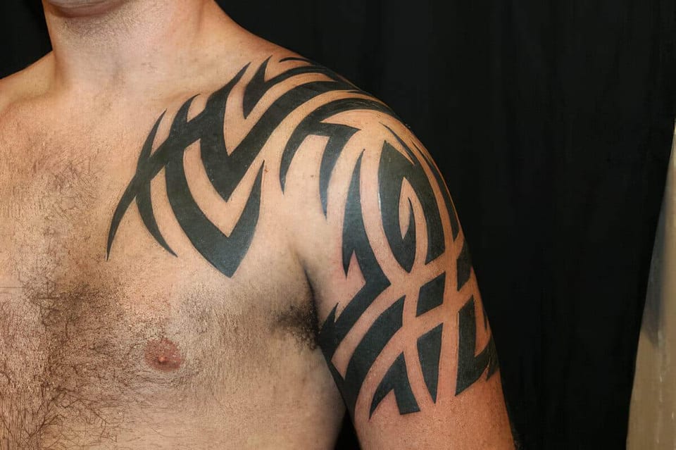 Black tribal curves tattooed on a shoulder and collarbone, tattooed by Seth Reynolds