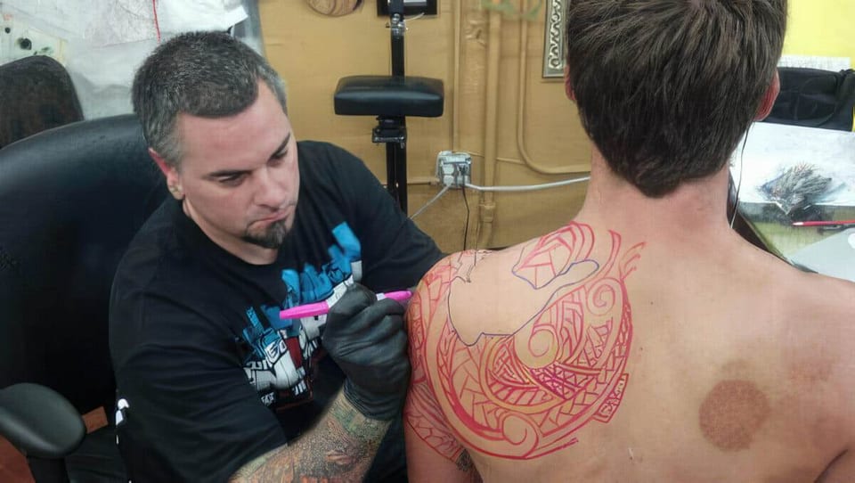 An artist working on a client's back, from the named Seth Reynolds Polynesian portfolio