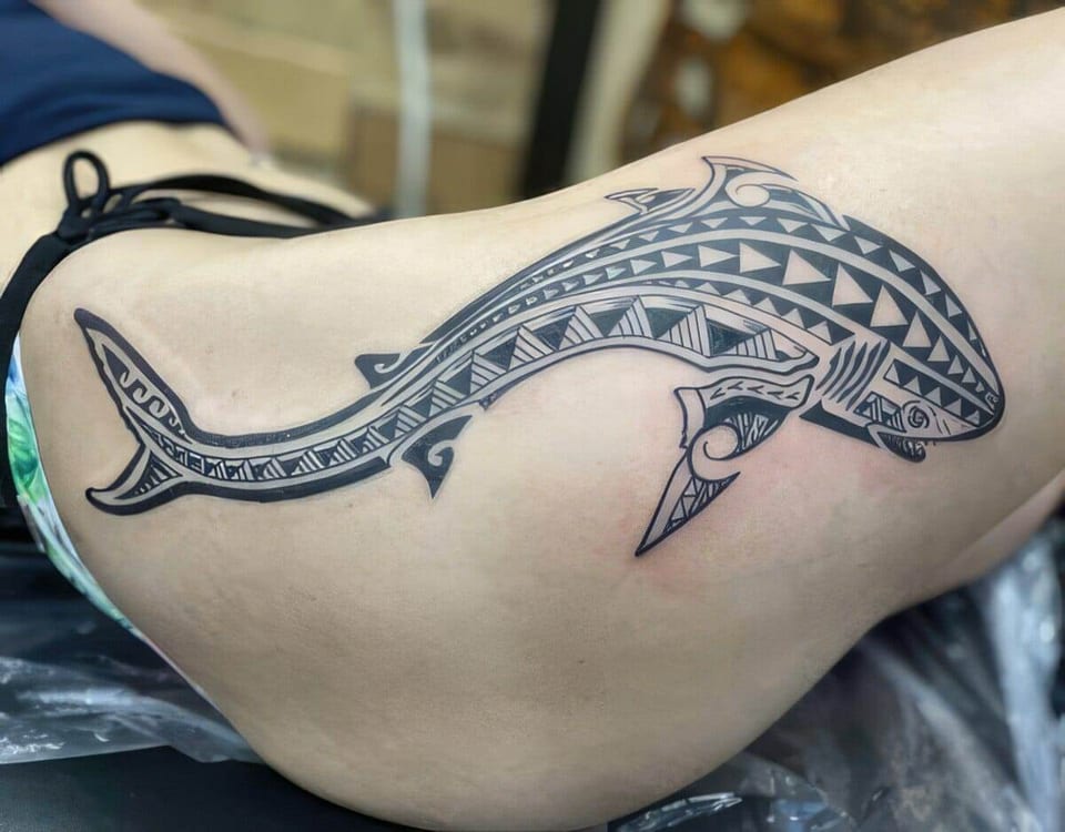 Black Polynesian-style shark tattooed along a thigh, tattooed by Seth Reynolds
