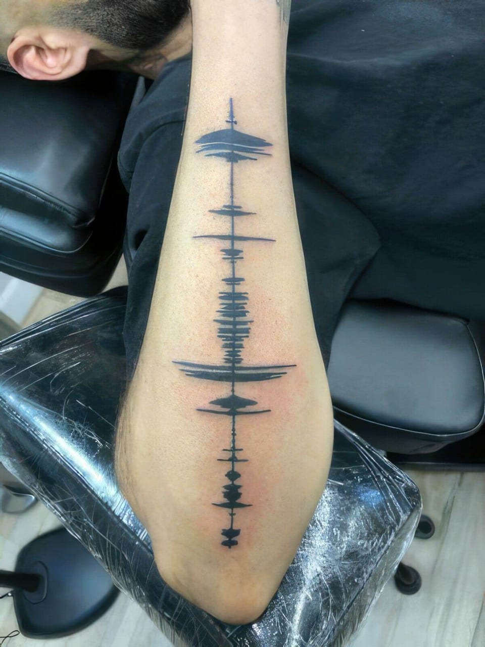 Black soundwave pattern tattooed down a forearm, tattooed by Seth Reynolds