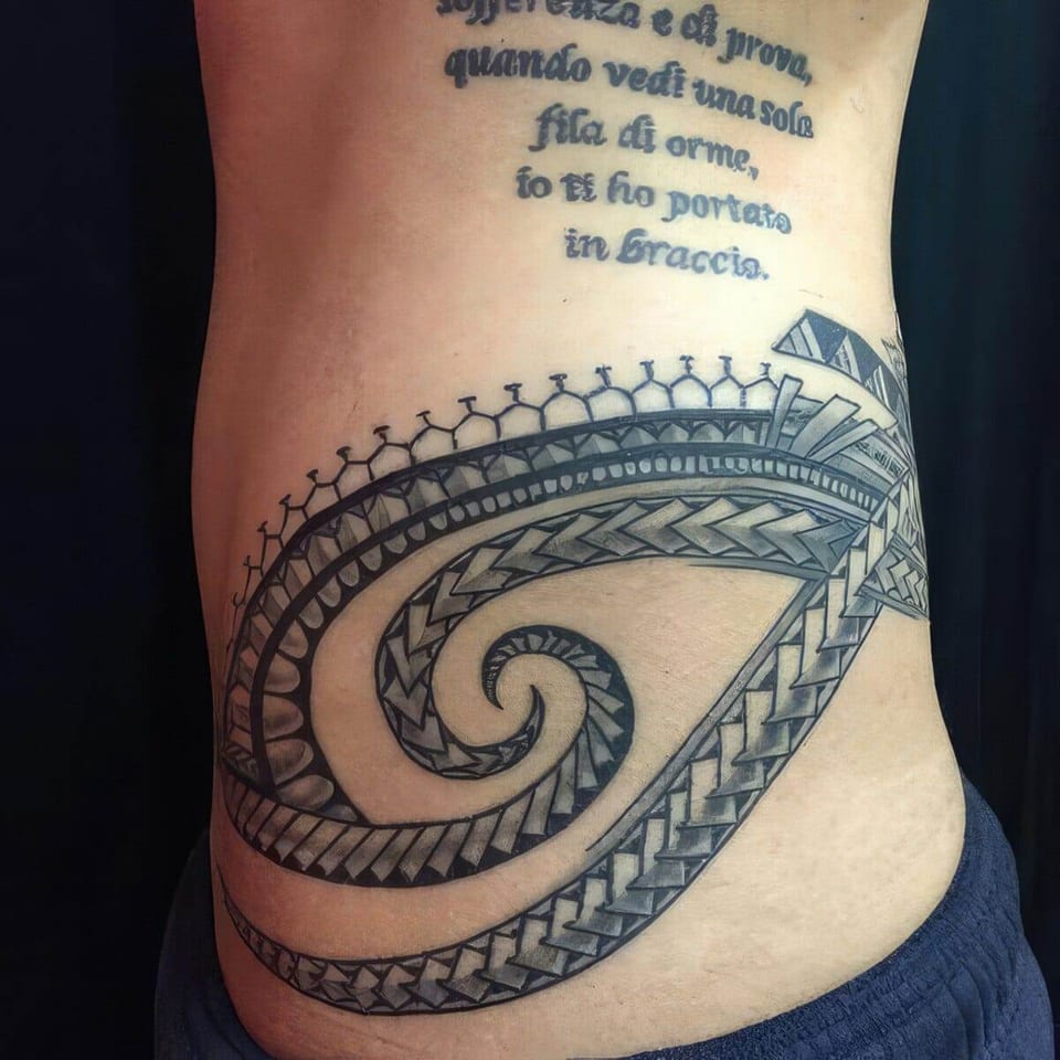Black Polynesian-style spiral band wrapping a side and lower back, with script lettering above, tattooed by Seth Reynolds
