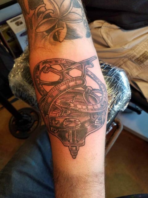 A black and grey illustrative navigation instrument with curved scales covers a forearm.